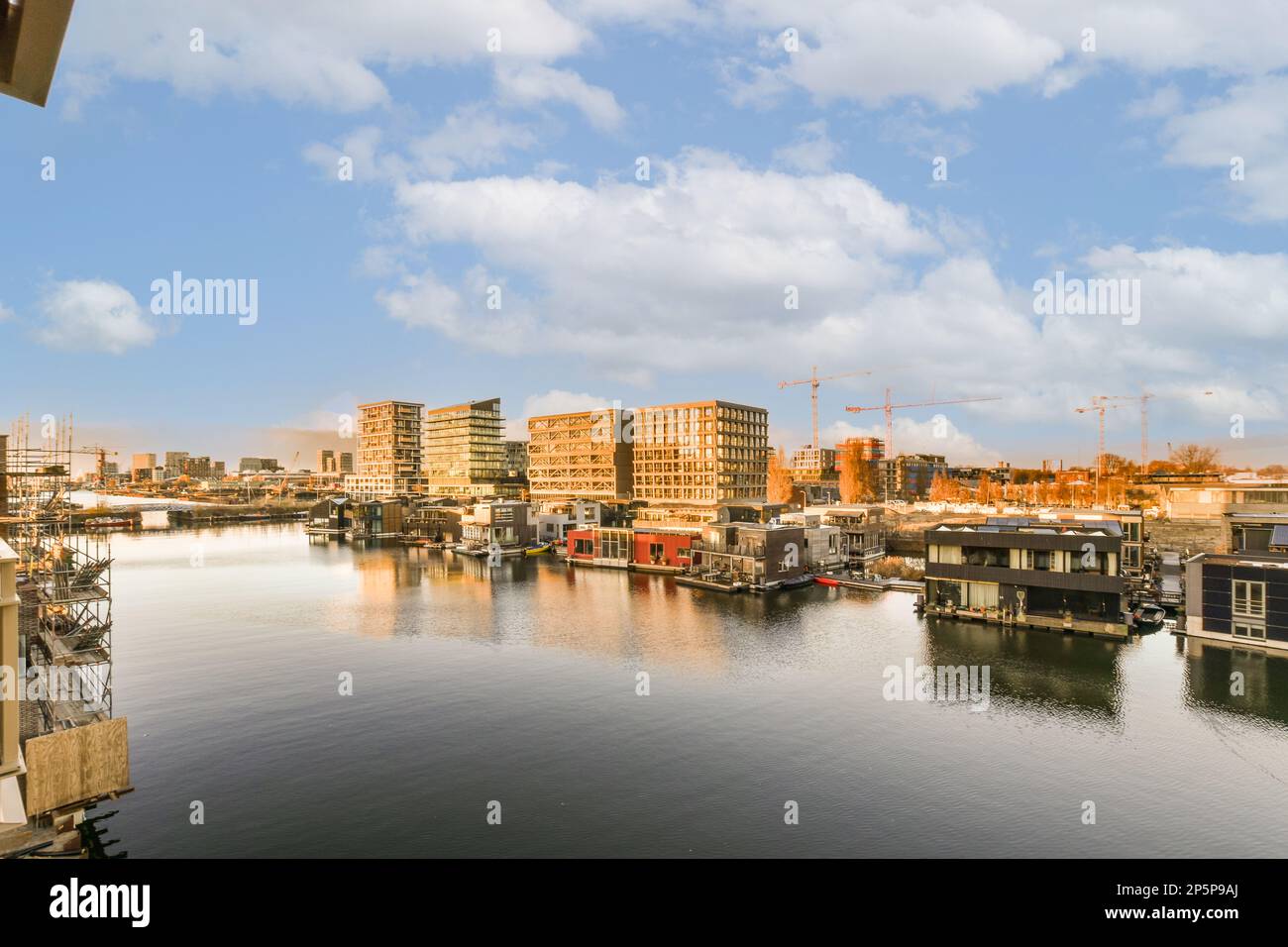 alcune barche in acqua e gli edifici sull'altro lato del fiume che sono in costruzione gru dietro di loro Foto Stock