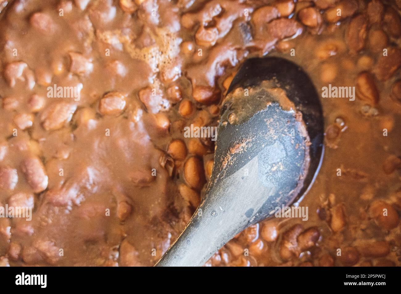Un primo piano di un cucchiaio di cioccolato caldo con fagioli in una ciotola Foto Stock