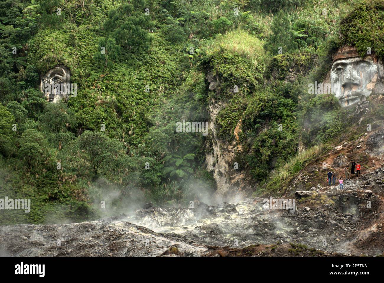 I campi di fumarole sotto il lato di una collina dove le facce giganti che illustrano Toar e Lumimuut, le figure ancestrali del popolo Minahasan, sono scolpite su Bukit Kasih (collina dell'amore), una popolare destinazione turistica religiosa situata nel villaggio di Kanonang, West Kawangkoan, Minahasa, North Sulawesi, Indonesia. In cima alla collina si trova un terreno pianeggiante dove sono costruiti luoghi di culto di tutte le religioni riconosciute in Indonesia. Dedicato a tutti i credenti e devoti religiosi, promuovendo gli spiriti dell'amore, della pace e della tolleranza; Bukit Kasih fu iniziato all'inizio del 2000. Foto Stock