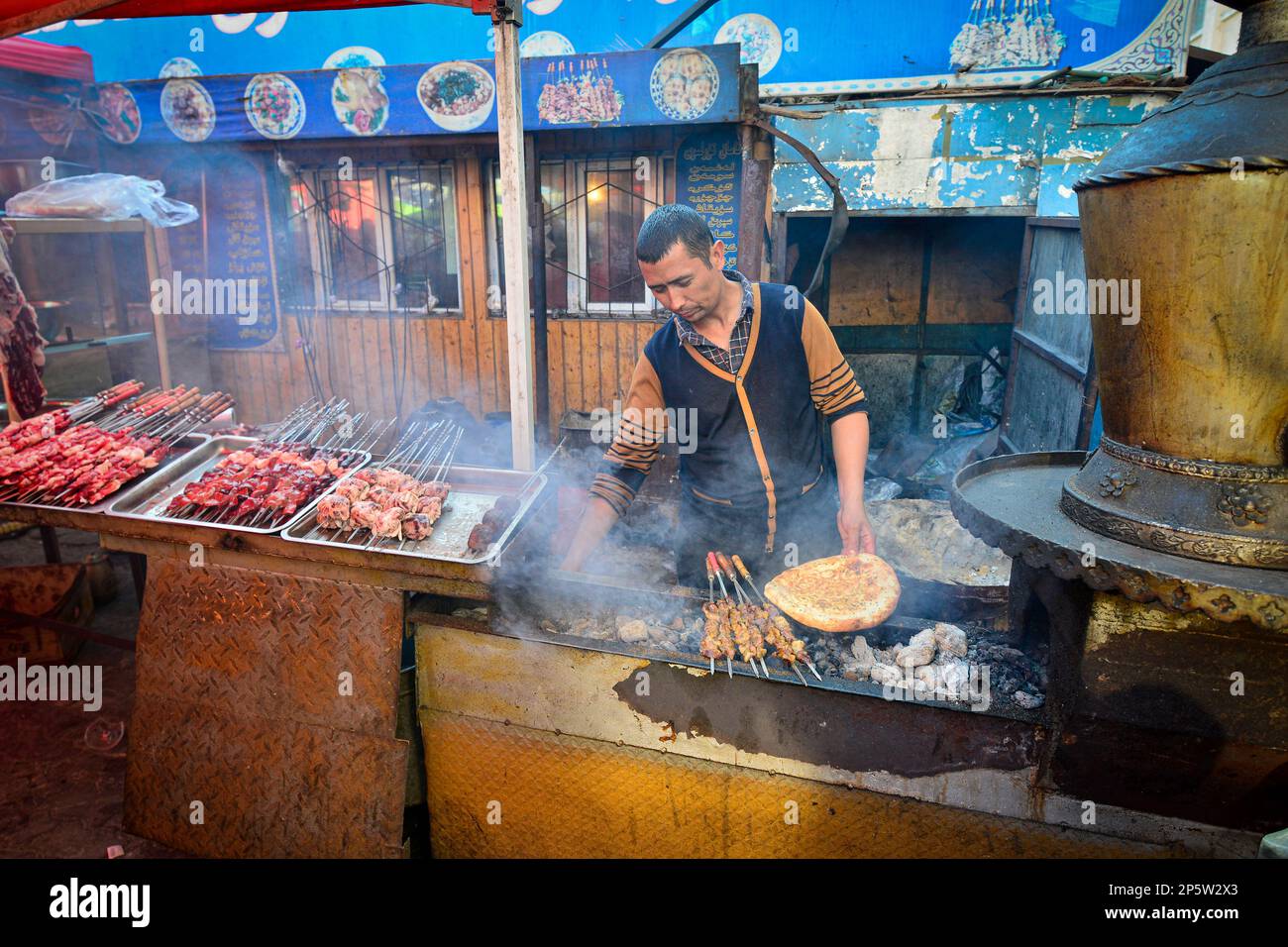 Venditori che vendono carne alla griglia e cibo locale Uighur in un mercato tradizionale a Urumqi, Xinjiang, Cina Foto Stock