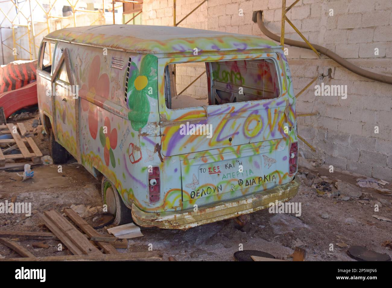 Un camper Volkswagen colorato hippy dipinto bug furgone che posa derelict in un magazzino nel Peloponneso, Grecia Foto Stock