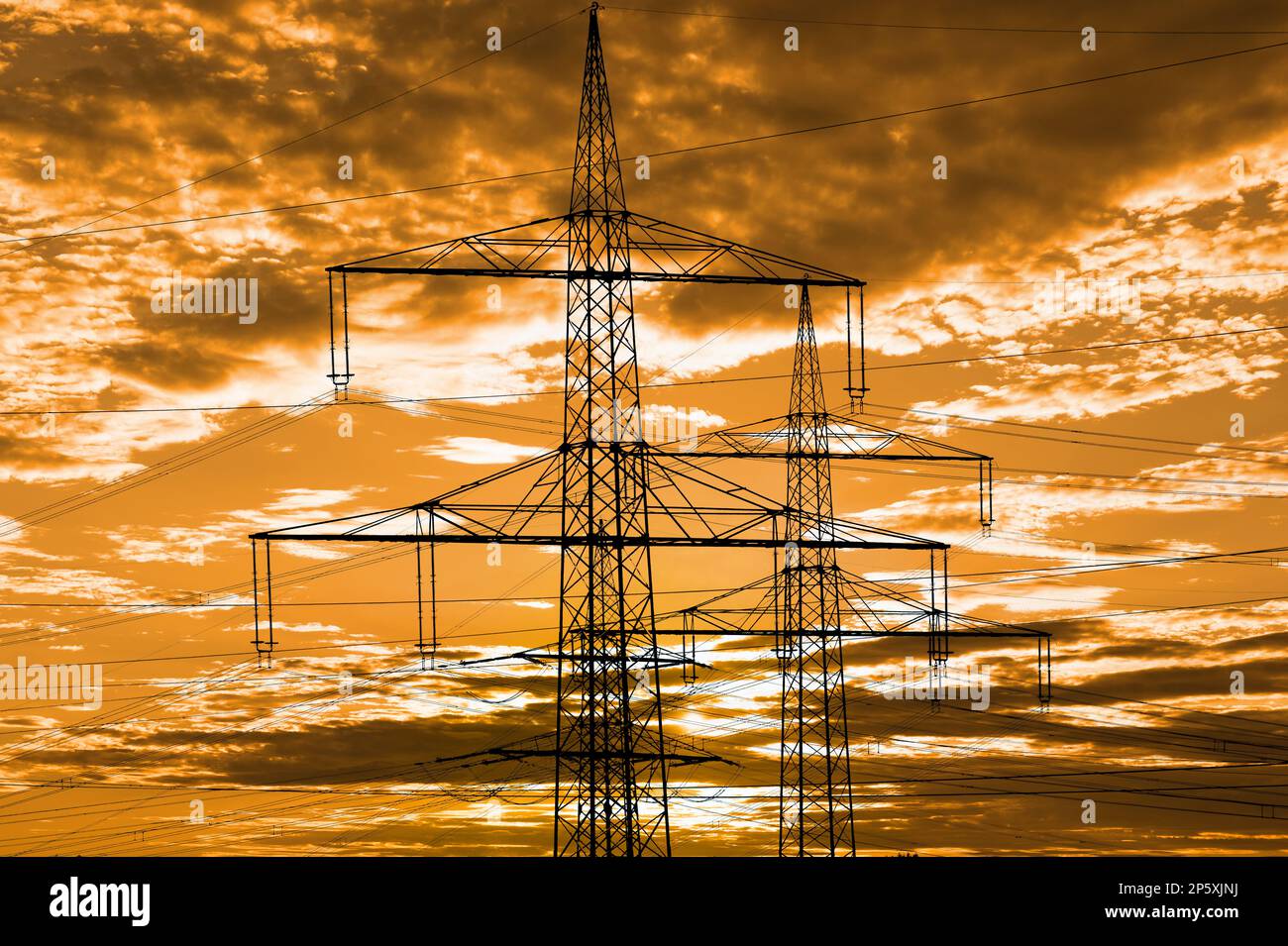 piloni ad alta tensione per l'elettricità e l'energia contro il cielo con nuvole drammatiche Foto Stock