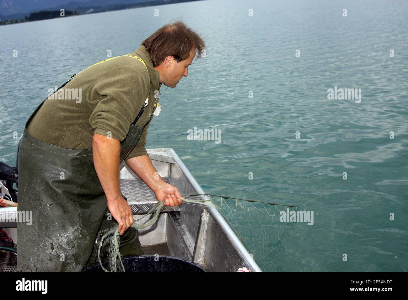 Pescatore in una barca su un lago trasporta in rete, Germania, Baviera, Allgaeu Foto Stock