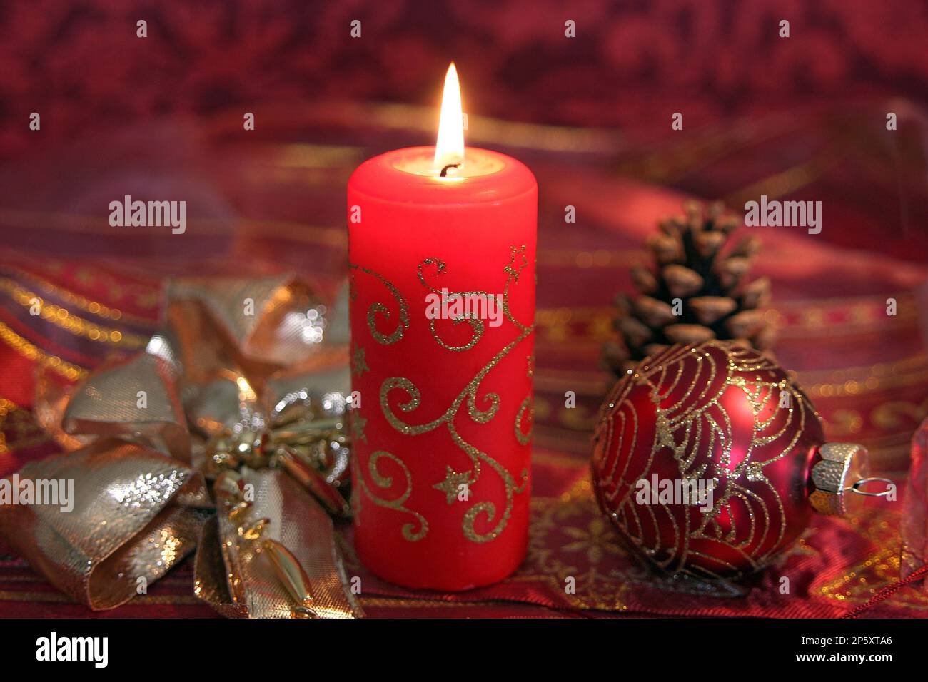 Palla di Natale rossa con cono di pino, nastro d'oro e candela bruciante, decorazione di Natale Foto Stock