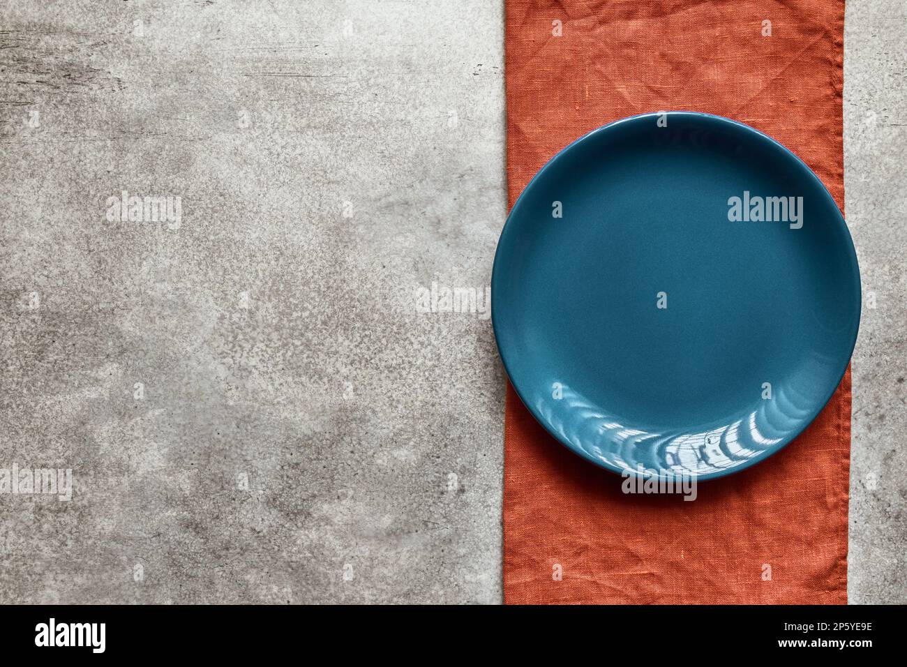 Piatto in ceramica blu vuoto su tovagliolo in terracotta, con spazio copia Foto Stock