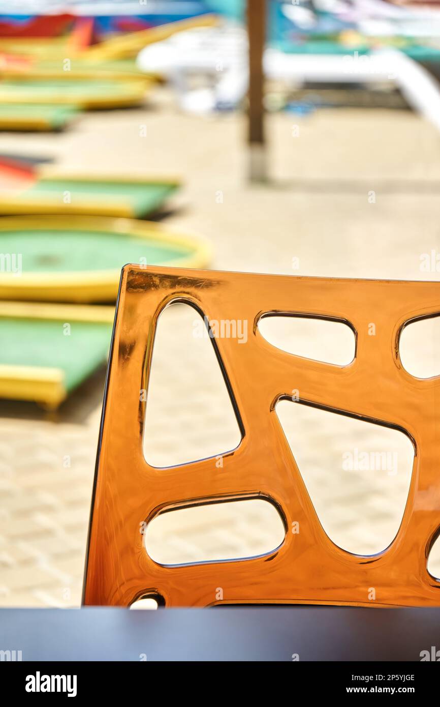 Schienale in vetro acrilico trasparente su fondo sfocato. Posto per sedersi in strada turistica caffè vicino al parco acquatico in giorno di sole closeup Foto Stock