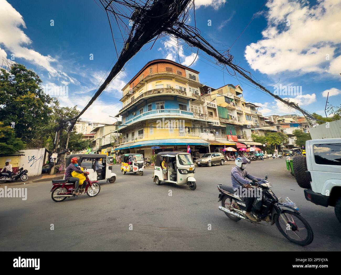 Una massa di cavi telefonici e di alimentazione appendono ad un incrocio stradale vicino ad un vecchio edificio di appartamenti nel centro di Phnom Penh, Cambogia. Foto Stock