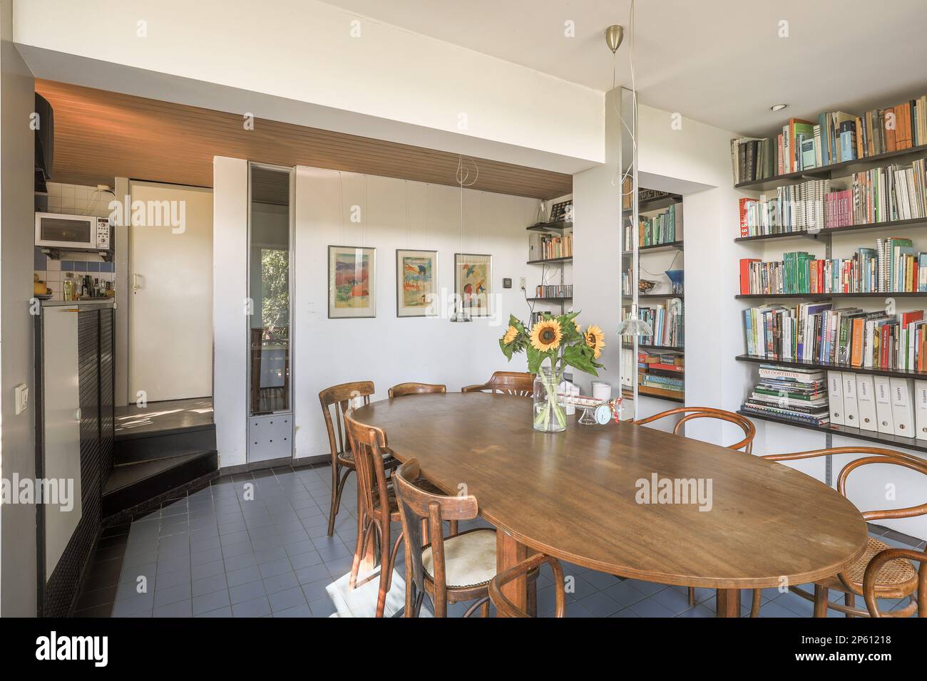 un tavolo da pranzo e sedie in una stanza con libri sulla parete dietro di esso, c'è una libreria piena di libri Foto Stock