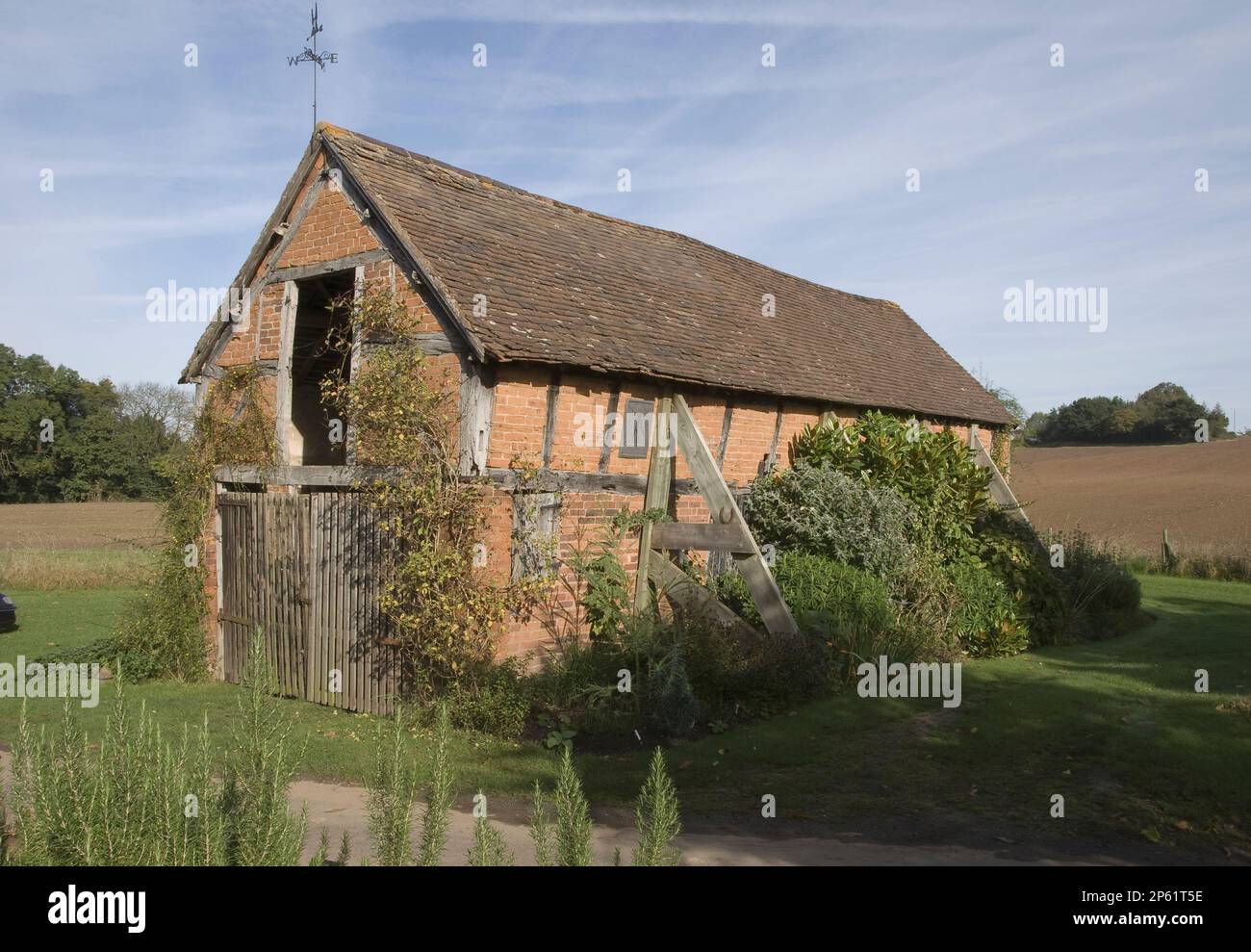 Vecchio fienile a graticcio in mattoni paese muri vecchio ripido tetto spiovente tegola puntone sostiene Eastgrove Foto Stock