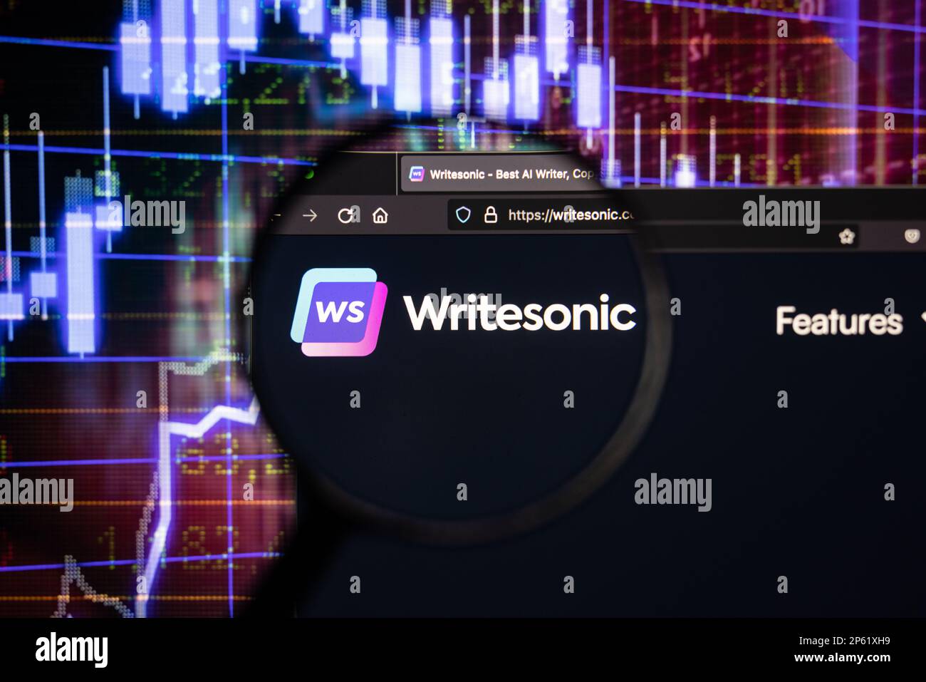 Logo Writesonic società su un sito web con blurry mercato azionario sviluppi in background, visto su uno schermo di un computer attraverso una lente di ingrandimento Foto Stock