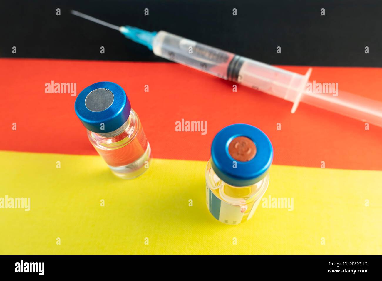 Pharmacology and Medicine Germany Concept. vaccino contro il coronavirus covid. Fiale di vaccino, siringa sullo sfondo della bandiera nazionale. natio Foto Stock