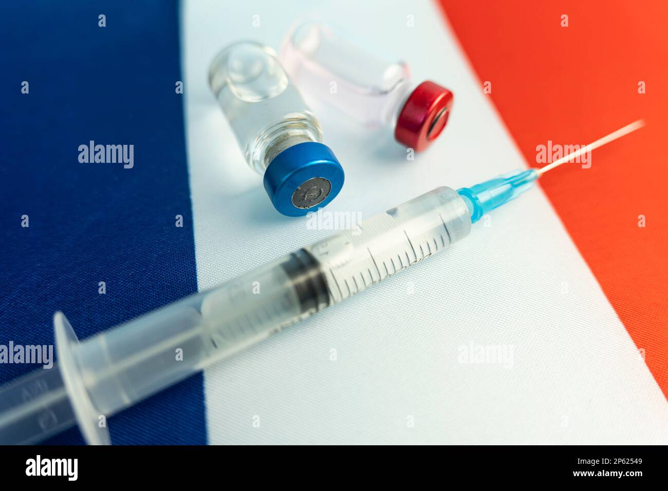 Pharmacology and Medicine France Concept. vaccino contro il coronavirus covid. Fiale di vaccino, siringa sullo sfondo della bandiera nazionale. nazione Foto Stock