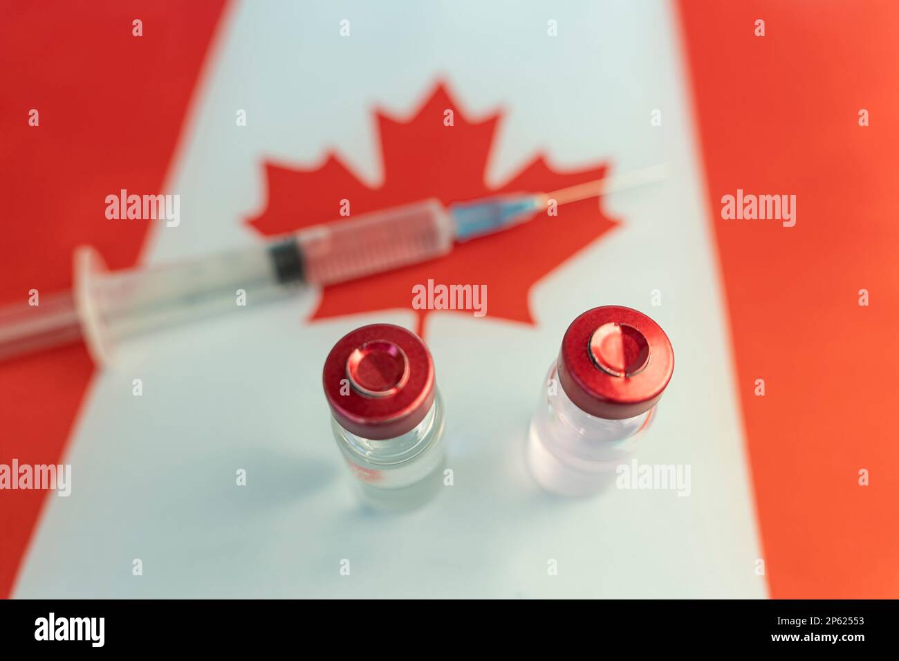 Pharmacology and Medicine Canada Concept. vaccino contro il coronavirus covid. Fiale di vaccino, siringa sullo sfondo della bandiera nazionale. nazione Foto Stock