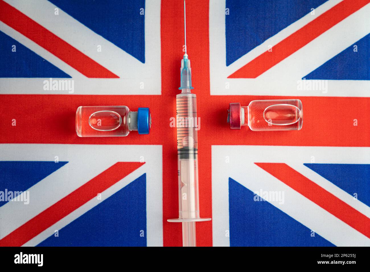Pharmacology and Medicine Great britain Concept. vaccino contro il coronavirus covid. Fiale di vaccino, siringa sullo sfondo della bandiera nazionale. Foto Stock