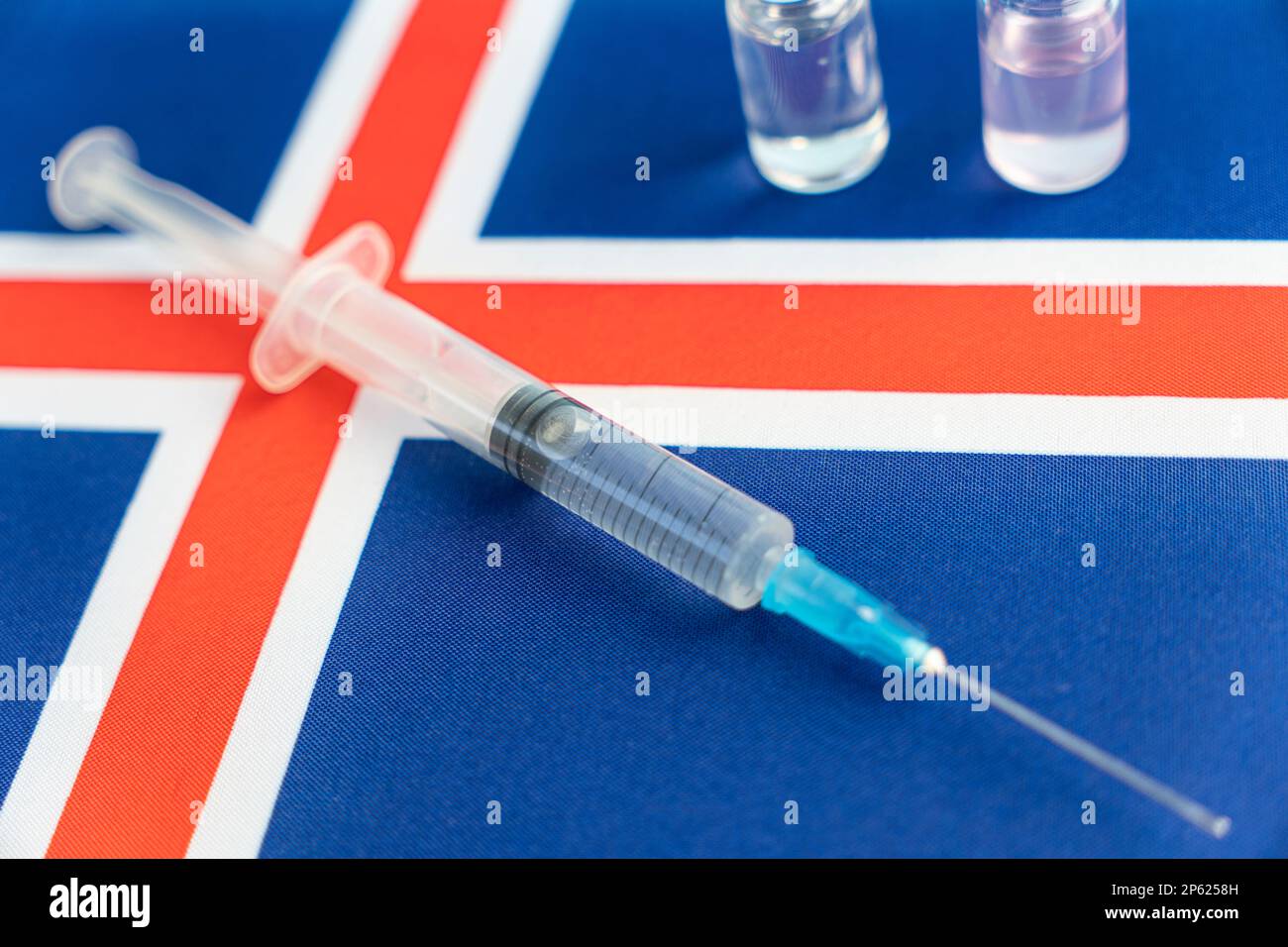 Concetto di Farmacologia e Medicina islanda. vaccino contro il coronavirus covid. Fiale di vaccino, siringa sullo sfondo della bandiera nazionale. natio Foto Stock