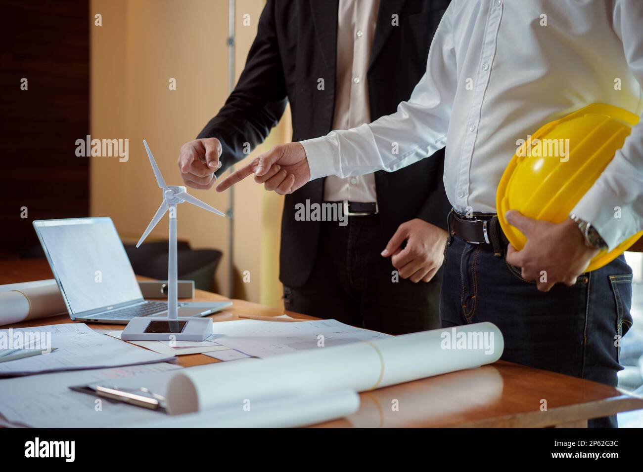 Team di architetti e ingegneri che discutano mentre lavorano con modelli e progetti di turbine eoliche. Uomini d'affari creativi che lavorano a una rinnovatrice Foto Stock Team di architetti e ingegneri che discutano mentre lavorano con modelli e progetti di turbine eoliche. Uomini d'affari creativi che lavorano a una rinnovatrice Foto Stock