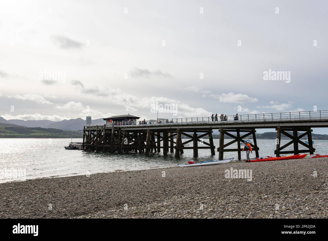 Beaumaris molo sulla costa di Anglesey, Galles del Nord. Turisti in attesa di gite in barca e kayak pronti per uscire in acqua. Foto Stock