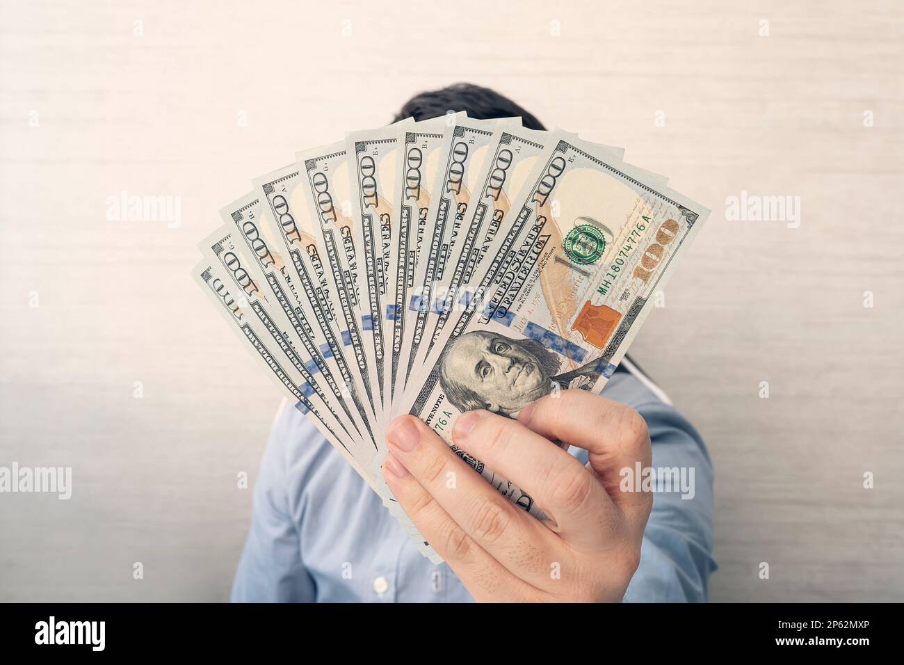 un giovane uomo tiene 1.000 dollari nelle sue mani su uno sfondo bianco in ufficio. Foto Stock