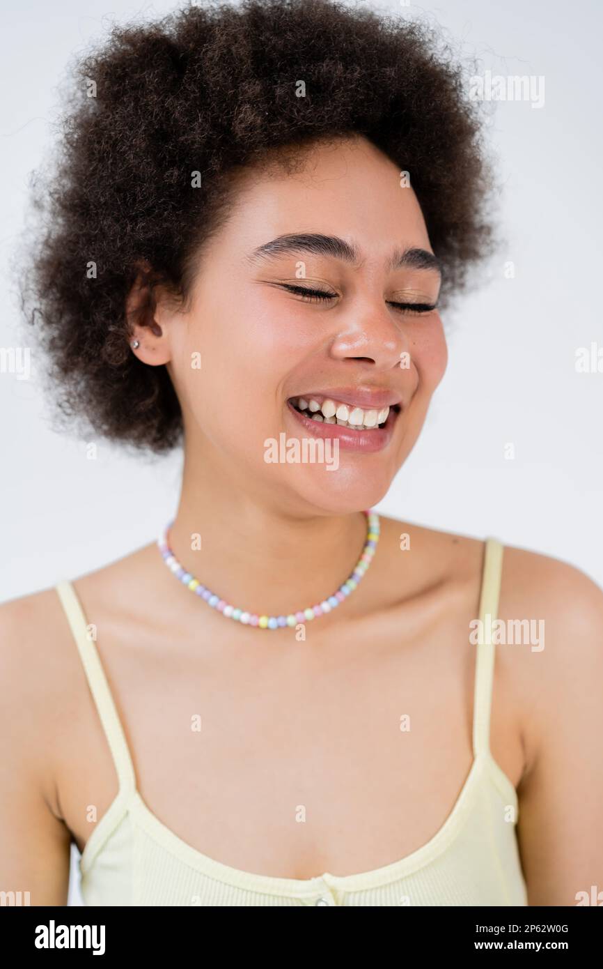 ritratto di donna afro-americana positiva in alto occhi chiusi isolato su grigio, immagine stock Foto Stock