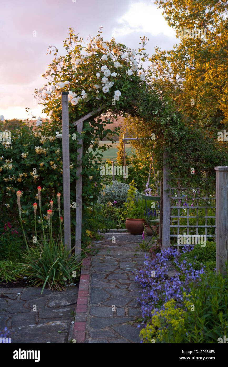 Grazioso arco in legno estende il giardino verso la campagna oltre Foto Stock