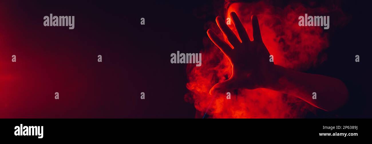 l'uomo fuma un hookah in un bar e soffia una grande nuvola di fumo con illuminazione al neon rosso Foto Stock