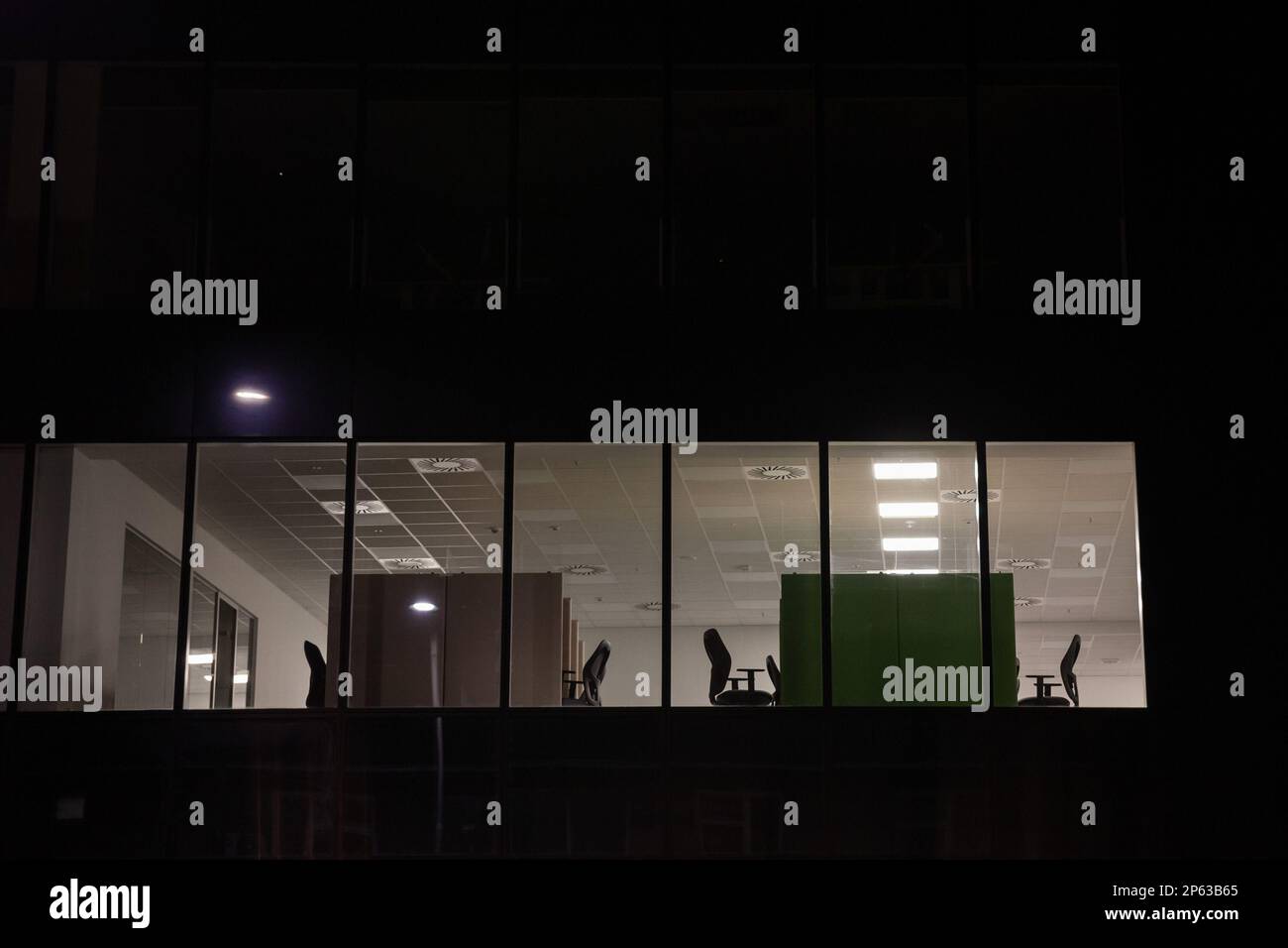 Immagine di una finestra di un ufficio di notte, con poche luci accese, in un quartiere degli affari, deserta. Foto Stock