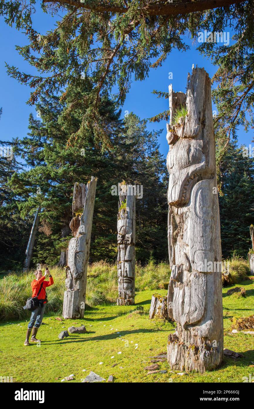 Fotografo con totem presso il sito patrimonio dell'umanità dell'UNESCO a SGang Gwaay, Haida Gwaii, British Columbia, Canada, Nord America Foto Stock