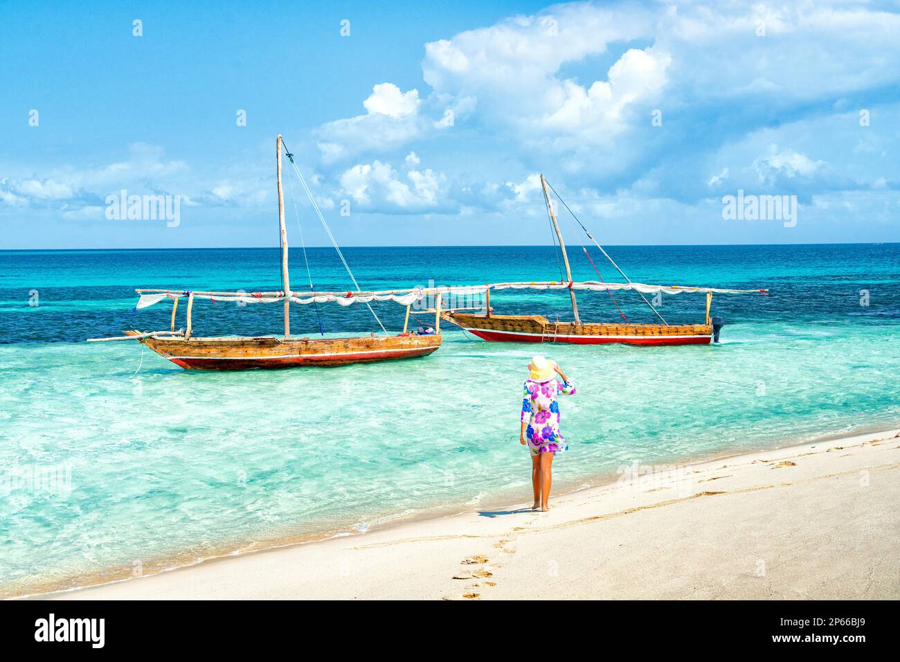 Donna allegra con cappello ammirando il mare cristallino in piedi su una spiaggia, Kwale Island, Zanzibar, Tanzania, Africa orientale, Africa Foto Stock