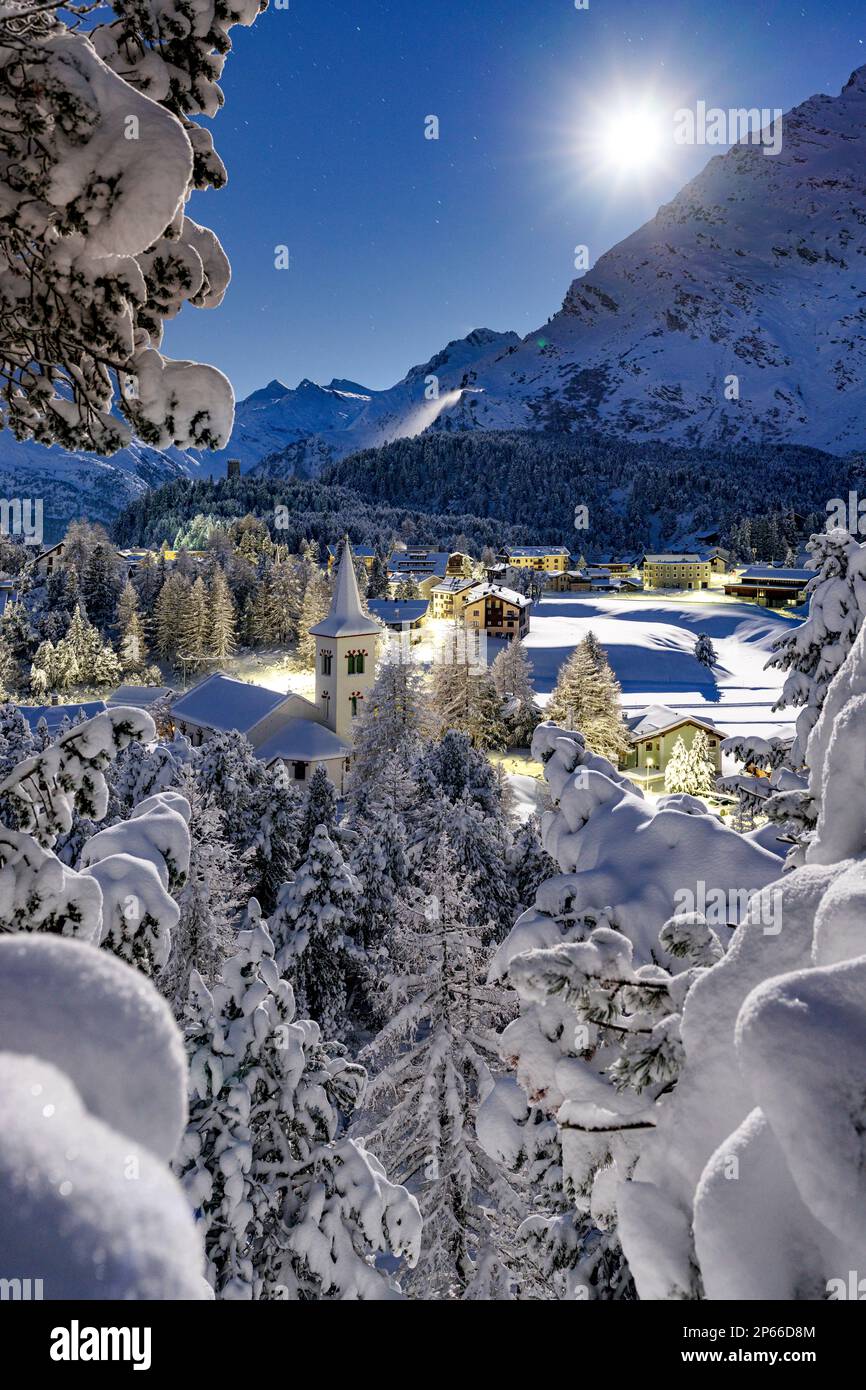Luna piena su Chiesa Bianca coperta di neve circondata da boschi, Maloja, Val Bregaglia, Engadina, Canton Graubunden, Svizzera, Europa Foto Stock