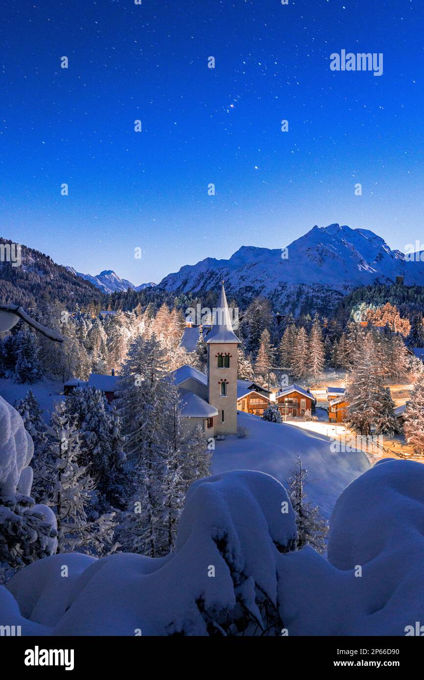 Chiesa Bianca coperta di neve sotto un cielo stellato e luminoso a Natale, Maloja, Bregaglia, Engadina, Cantone di Graubunden, Svizzera, Europa Foto Stock