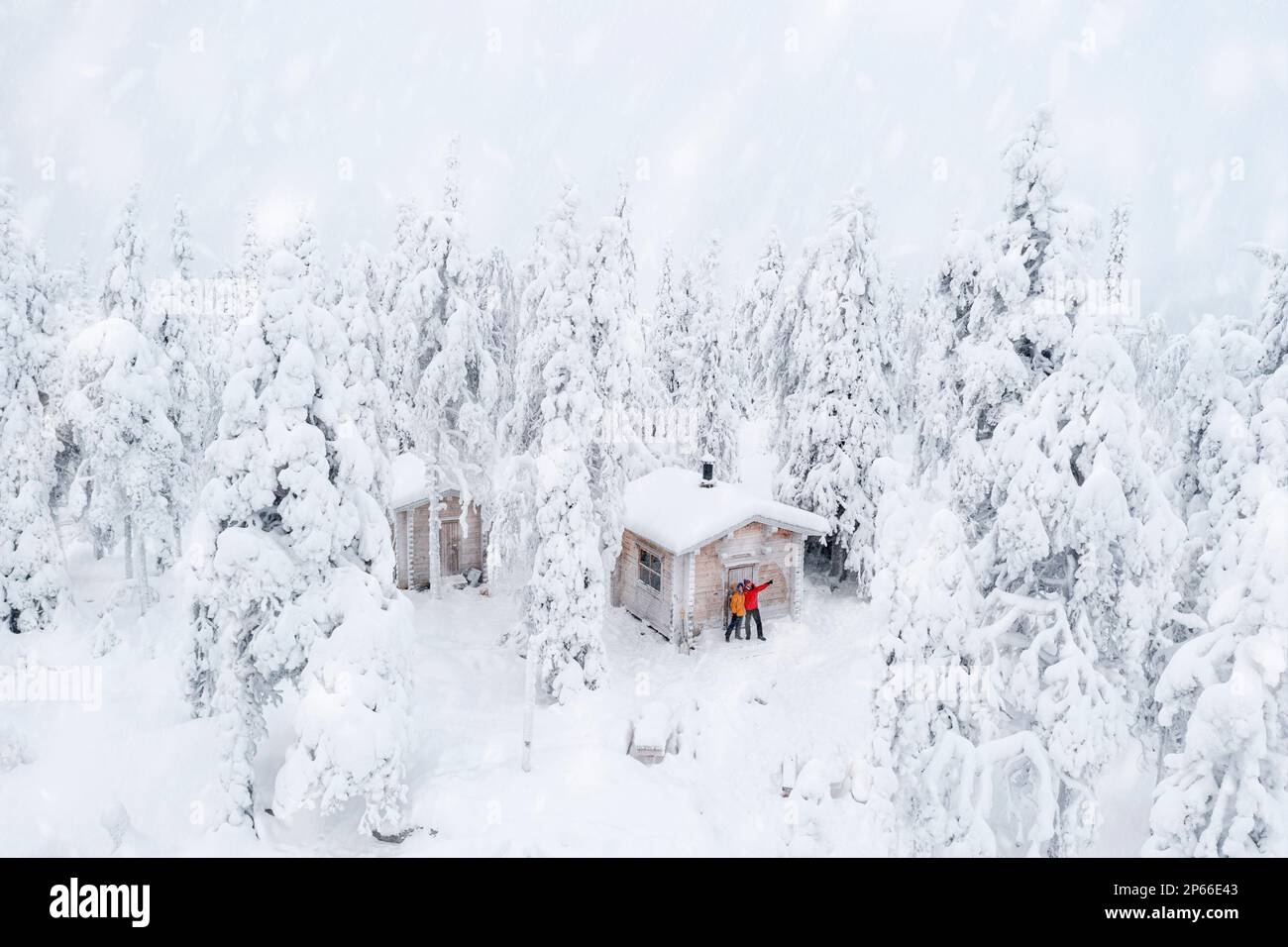 Vista aerea di una coppia felice godendo le vacanze invernali in una capanna ghiacciata nella foresta innevata, ISO Syote, Ostrobothnia settentrionale, Lapponia, Finlandia Foto Stock
