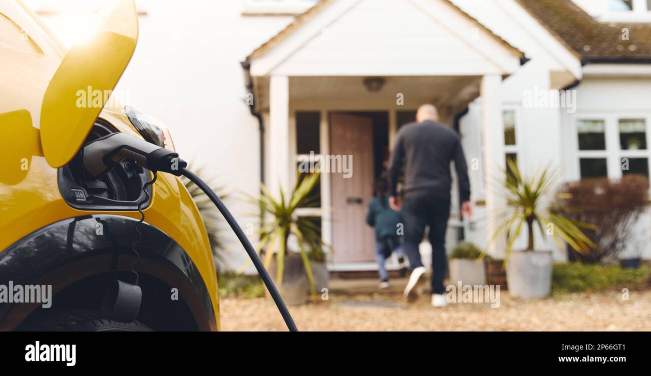 Ricarica di auto elettriche sul vialetto di accesso all'esterno della casa Foto Stock