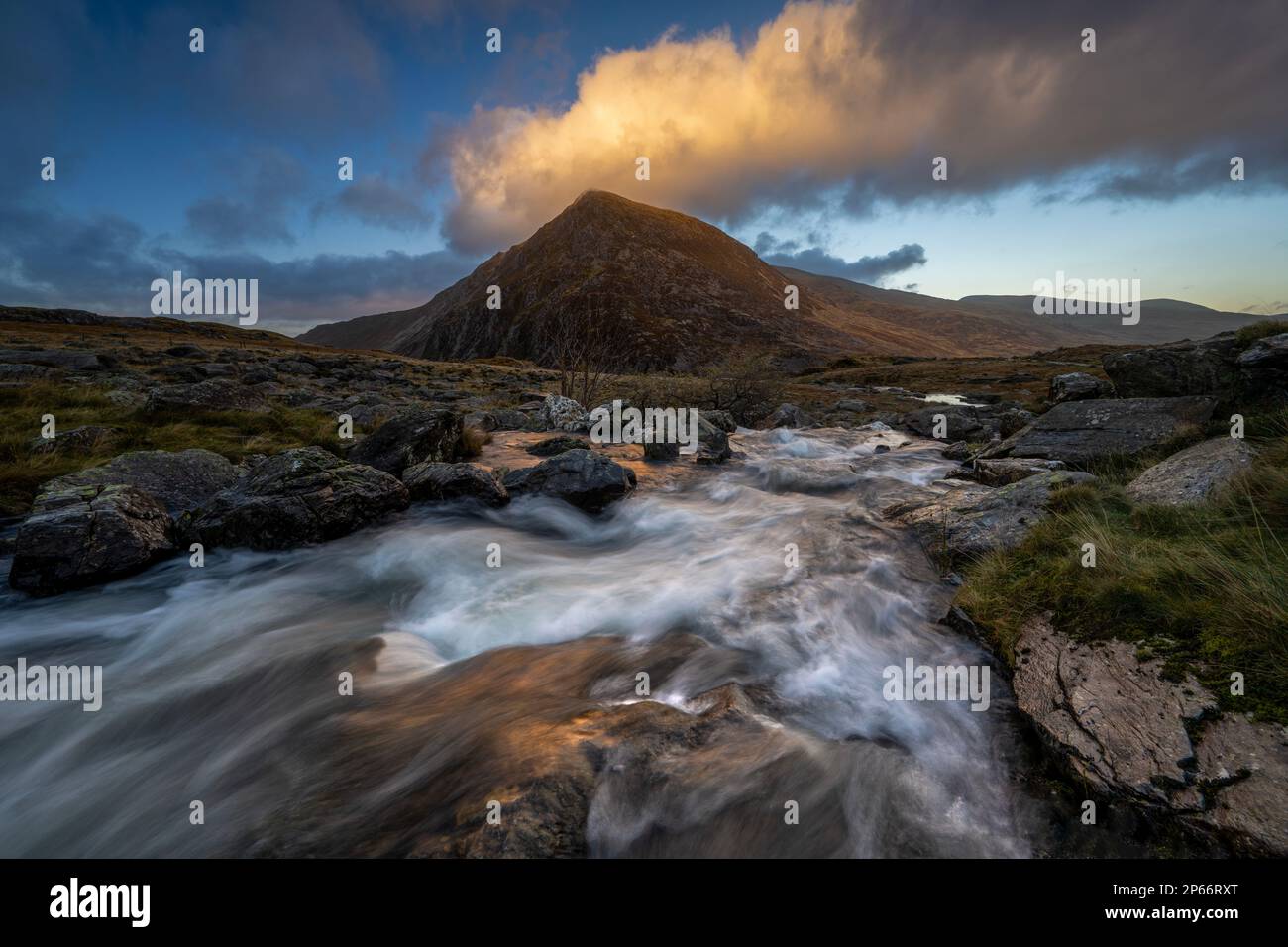 Acqua che scende giù una caduta verso Llyn Dinas sostenuto con catena montuosa, Snowdonia, Galles, Regno Unito, Europa Foto Stock