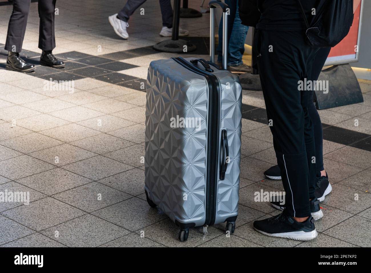 I passeggeri sono in piedi accanto a una valigia su ruote. Primo piano. Foto Stock