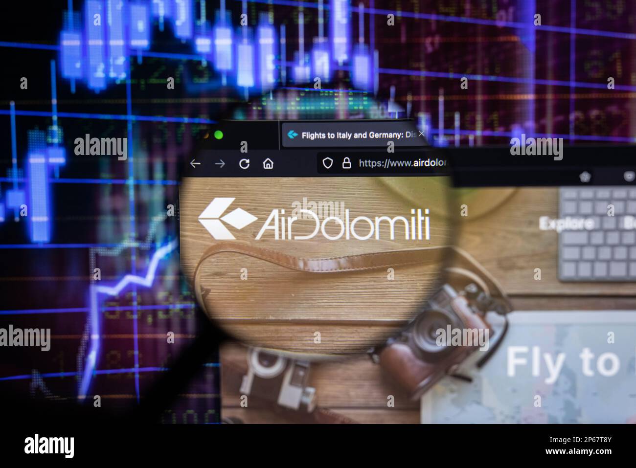 Logo della compagnia aerea Air Dolomiti su un sito web con un'evoluzione sfocata del mercato azionario sullo sfondo, vista attraverso una lente d'ingrandimento Foto Stock