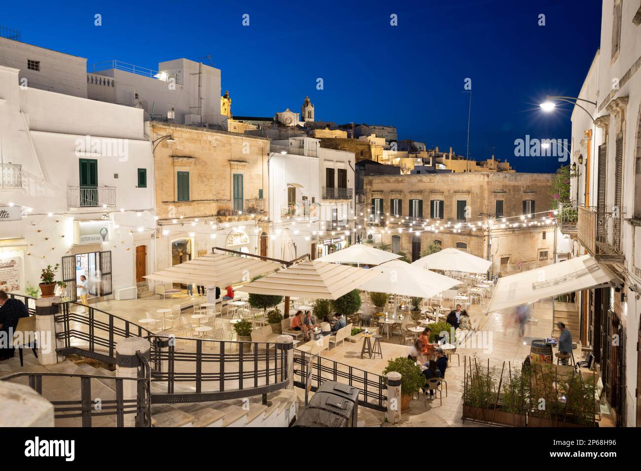 Ristoranti illuminati di sera in Piazza della libertà, Ostuni, provincia di Brindisi, Puglia, Italia, Europa Foto Stock