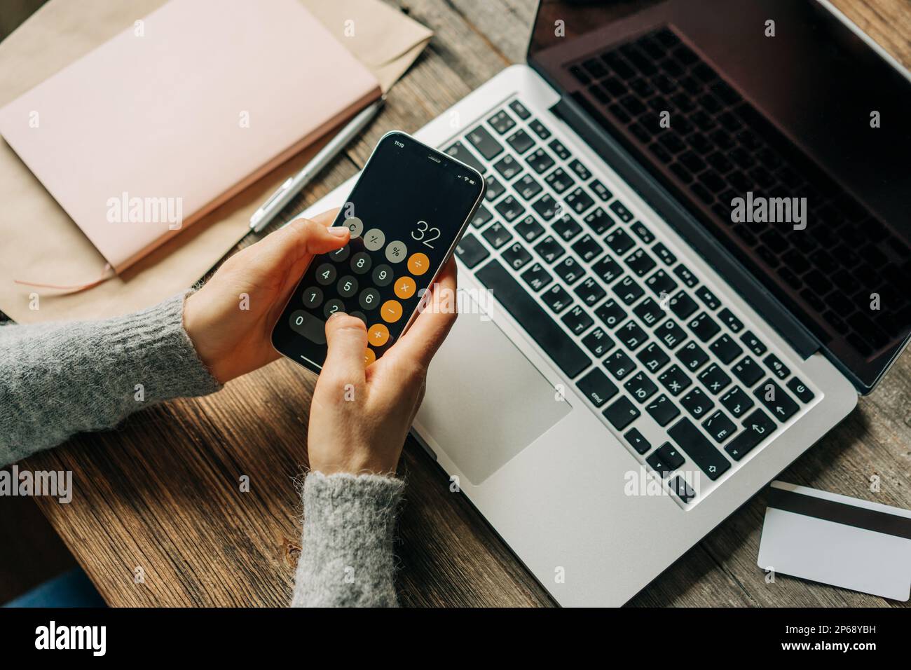 Donna irriconoscibile lavora utilizzando la calcolatrice e il computer portatile sul posto di lavoro. Foto Stock