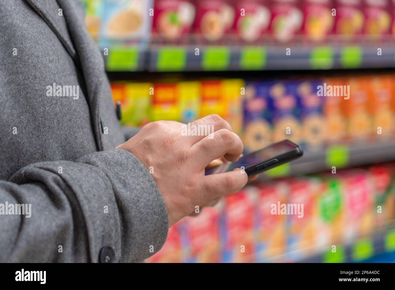 Primo piano delle mani degli uomini utilizzando uno smartphone in un supermercato. Foto Stock