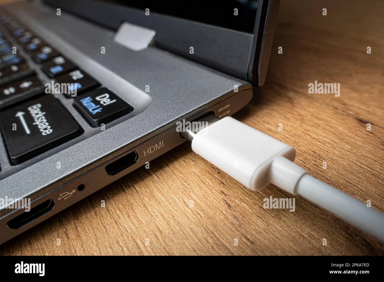 L'adattatore USB del cavo sotto il connettore di tipo C è installato nel computer portatile sullo sfondo di un tavolo di legno Foto Stock