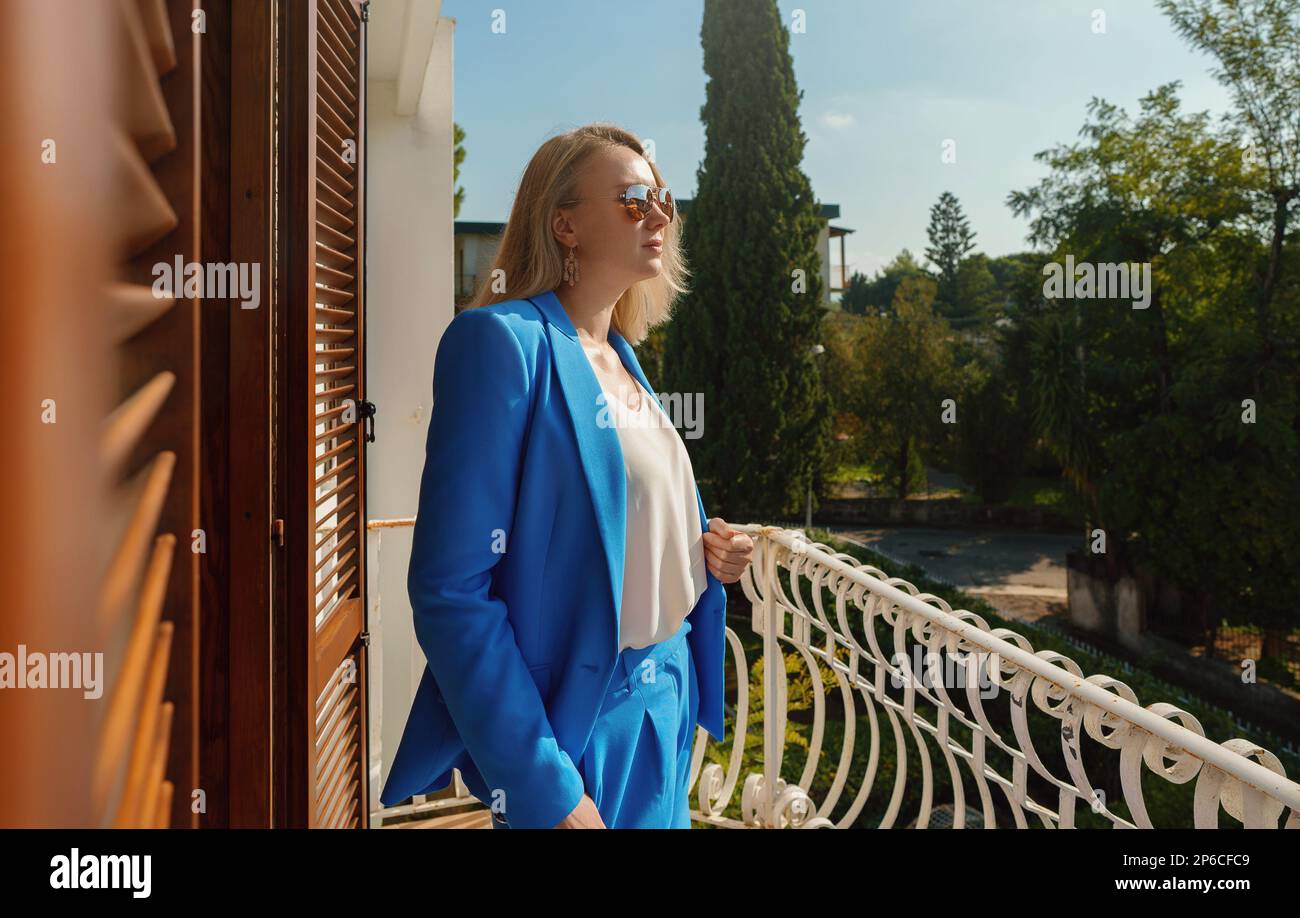 Donna in tuta si erge sul balcone di una casa privata. Foto Stock