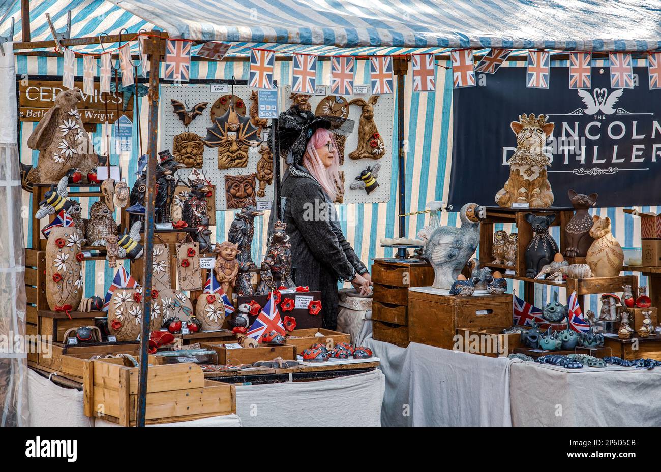 Un commerciante di mercato femminile che vende ceramiche e ornamenti in attesa del suo prossimo cliente. Foto Stock