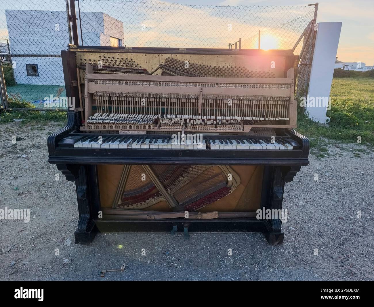 Vecchio pianoforte abbandonato in strada con un tramonto sullo sfondo Foto Stock
