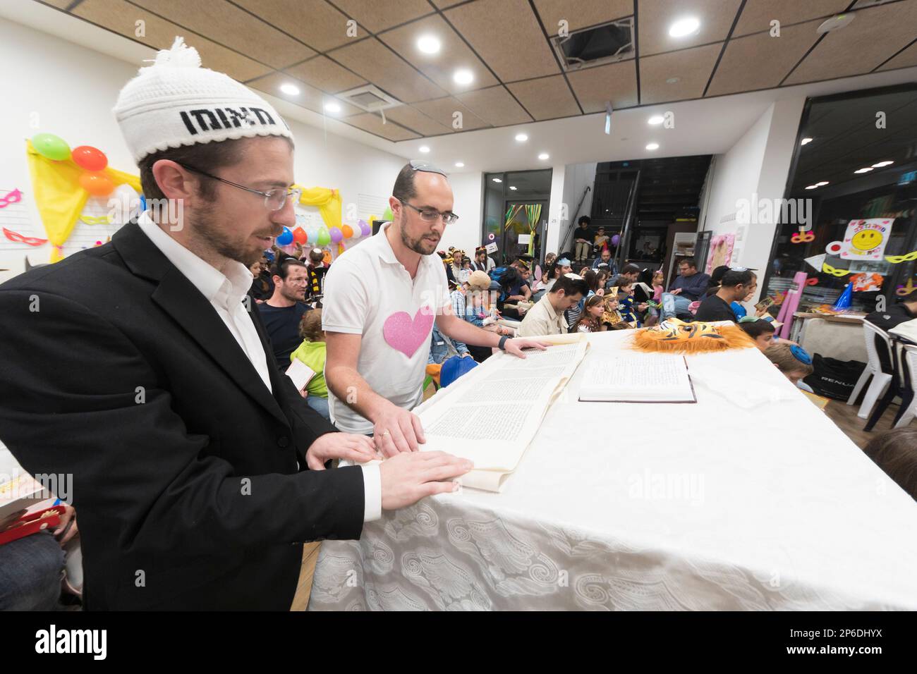 Harish, Israele. Lettura del rotolo di Esther durante la festa ebraica di Purim. In questa festa gli ebrei vestono in costume, leggono il libro di Esther, una storia su un complotto antiebraico fallito nell'antica Persia, e fanno una racchetta con i clapper e altri dispositivi assortiti per la produzione del rumore ogni volta che viene menzionato il nome di Haman, il principale antagonista. Foto Stock