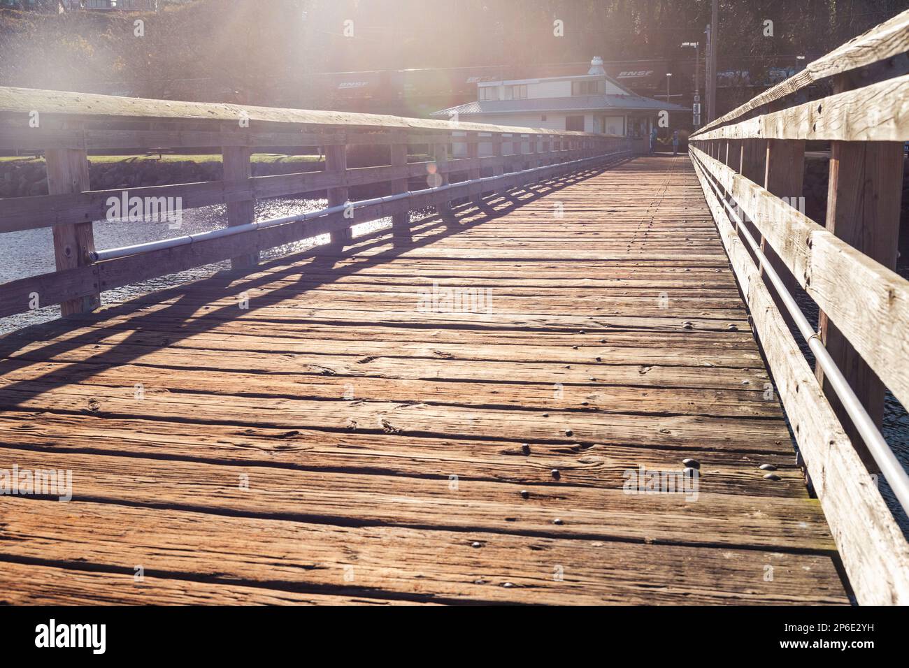 Molo di legno che conduce a terra con luce solare Foto Stock