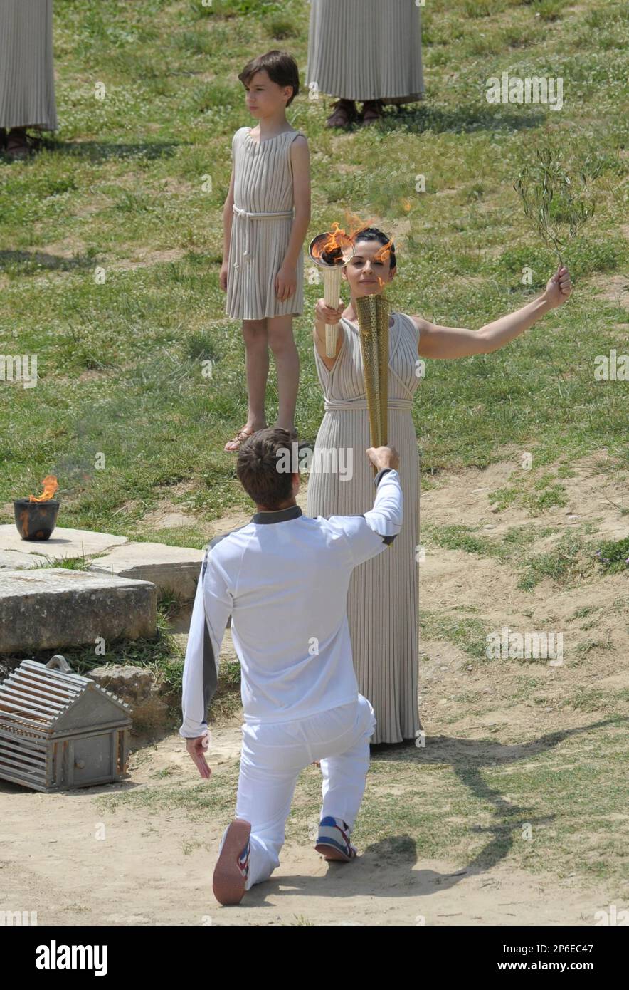 An actress Ino Menegak (C), playing the role of high priestess relays the Olympic flame to Spyros Gianniotis (below), Greek swimmer, as the first torchbearer for the London 2012 Olympic Games, during the torch-lighting ceremony in the ancient site, Olympia, Greece, on May 10, 2012. ( The Yomiuri Shimbun via AP Images ) Foto Stock