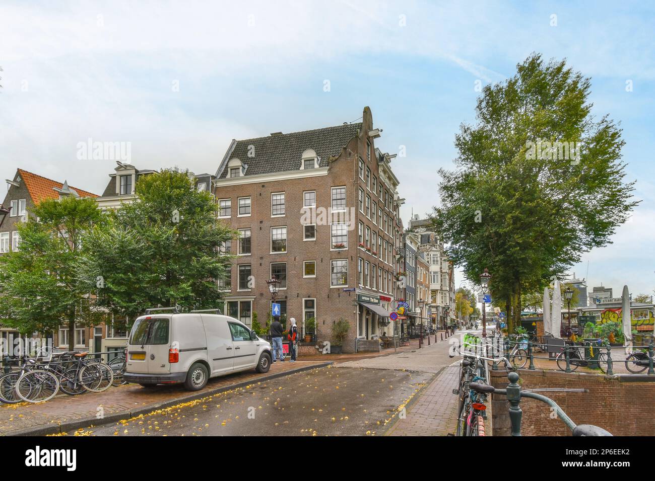 Amsterdam, Paesi Bassi - 10 aprile, 2021: Una strada cittadina con molti edifici e biciclette parcheggiate sul lato della strada, di fronte a un furgone bianco Foto Stock