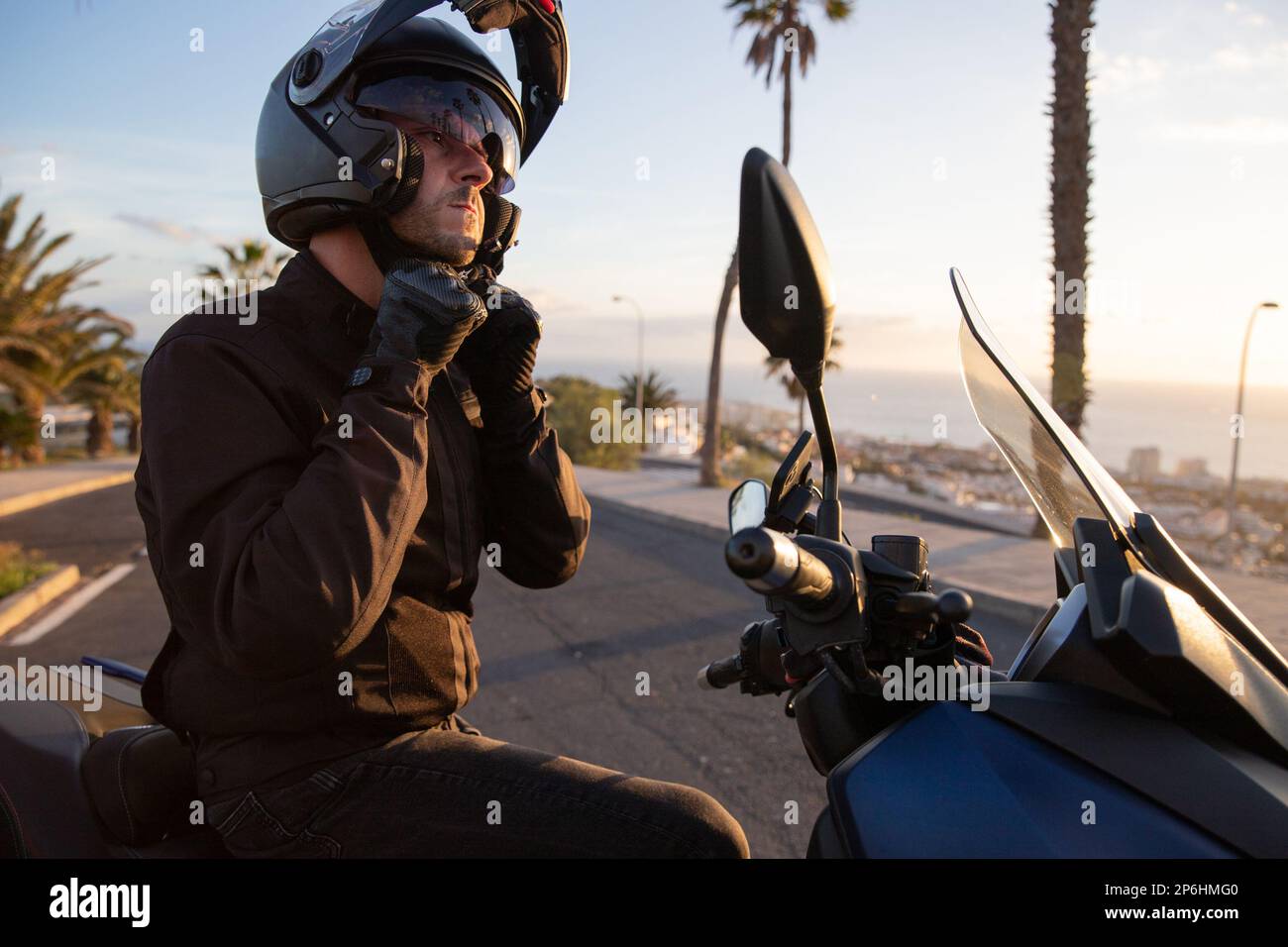 Un motociclista seduto sulla sua moto indossa un casco, la sicurezza di guida. Foto Stock