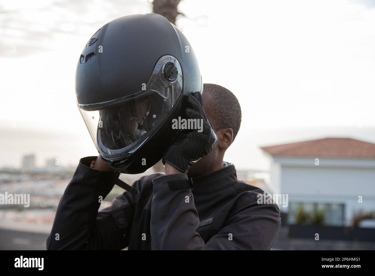 Un motociclista indossa il casco prima di partire, concetto di sicurezza stradale Foto Stock