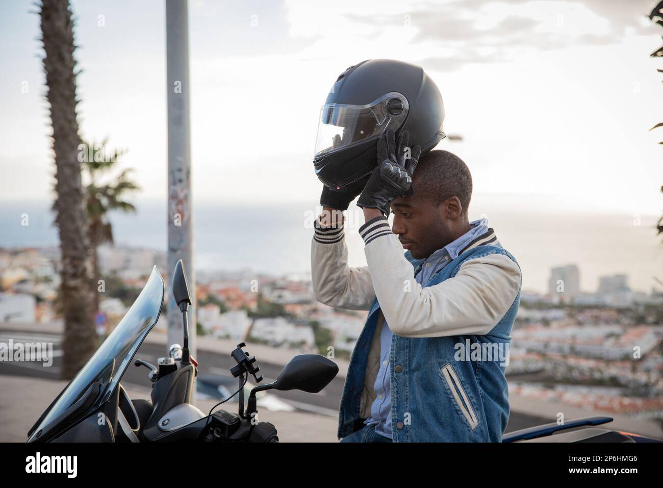 Il motociclista afro-americano indossa un casco mentre si siede sulla sua moto Foto Stock
