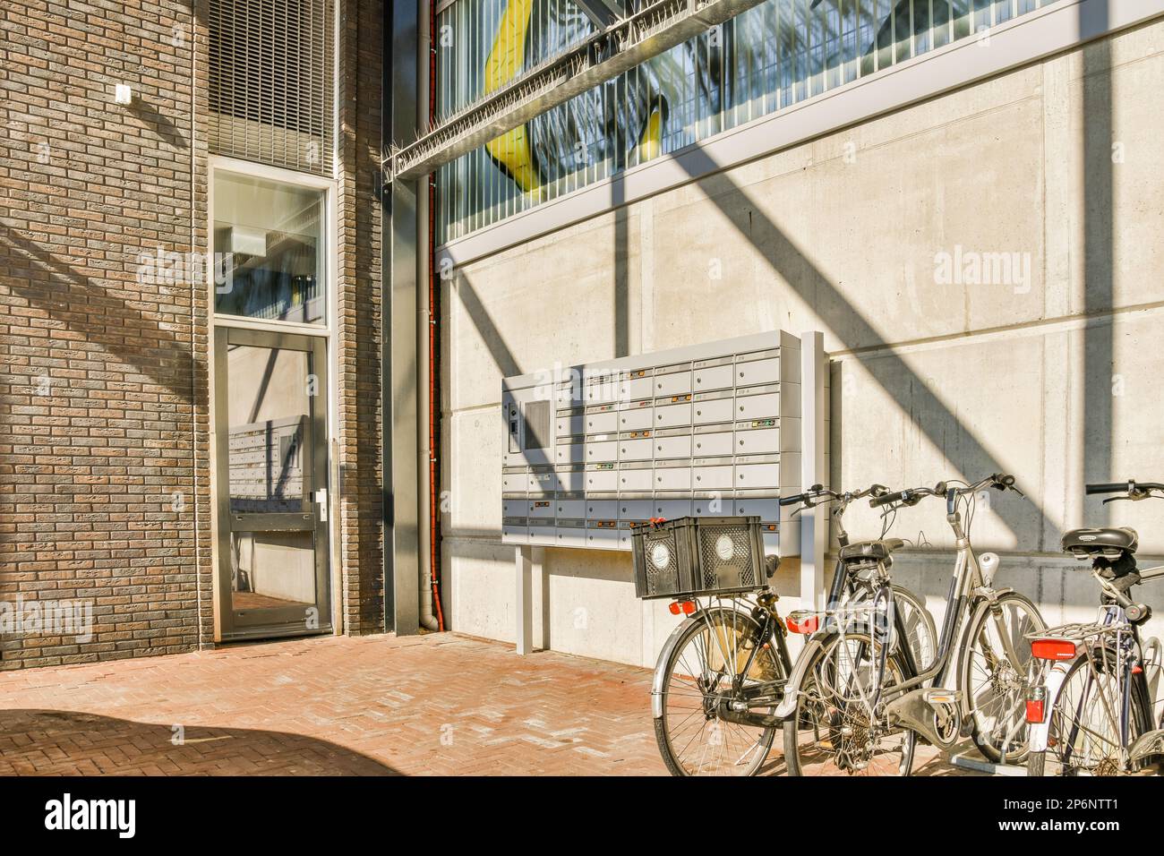 due biciclette parcheggiate l'una accanto all'altra davanti a un edificio con il sole che splende attraverso le finestre Foto Stock